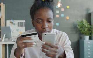 Woman holding credit card and smartphone for online shopping.