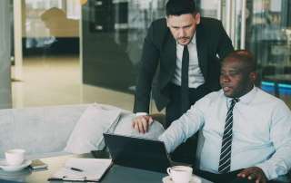 Two businessmen collaborating on a laptop in an office.