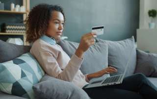 Woman using laptop and credit card on sofa